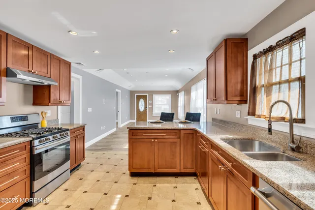 a kitchen with stainless steel appliances granite countertop a stove a sink and a refrigerator