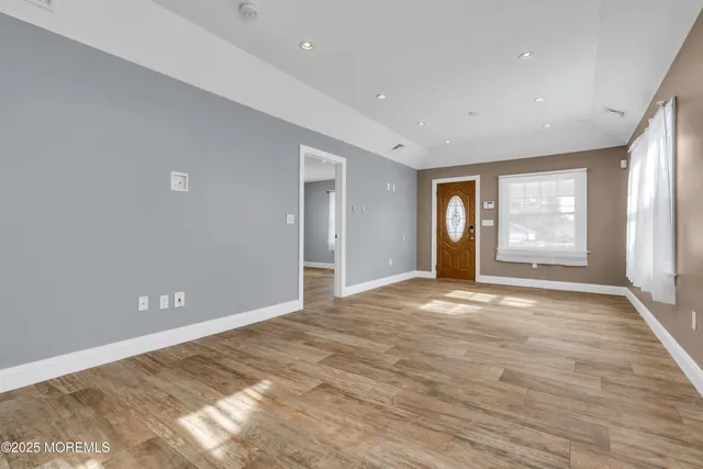 a view of an empty room with window and wooden floor