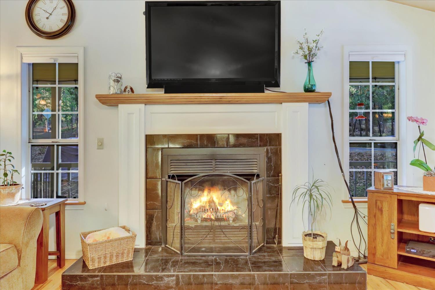 12746 Quaker Hill Cross Road Nevada City, CA 95959 - Photo 9 of 99 a living room with a fireplace a flat screen tv and a large window