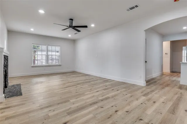 an empty room with wooden floor ceiling fan and windows