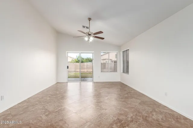 an empty room with chandelier fan and windows