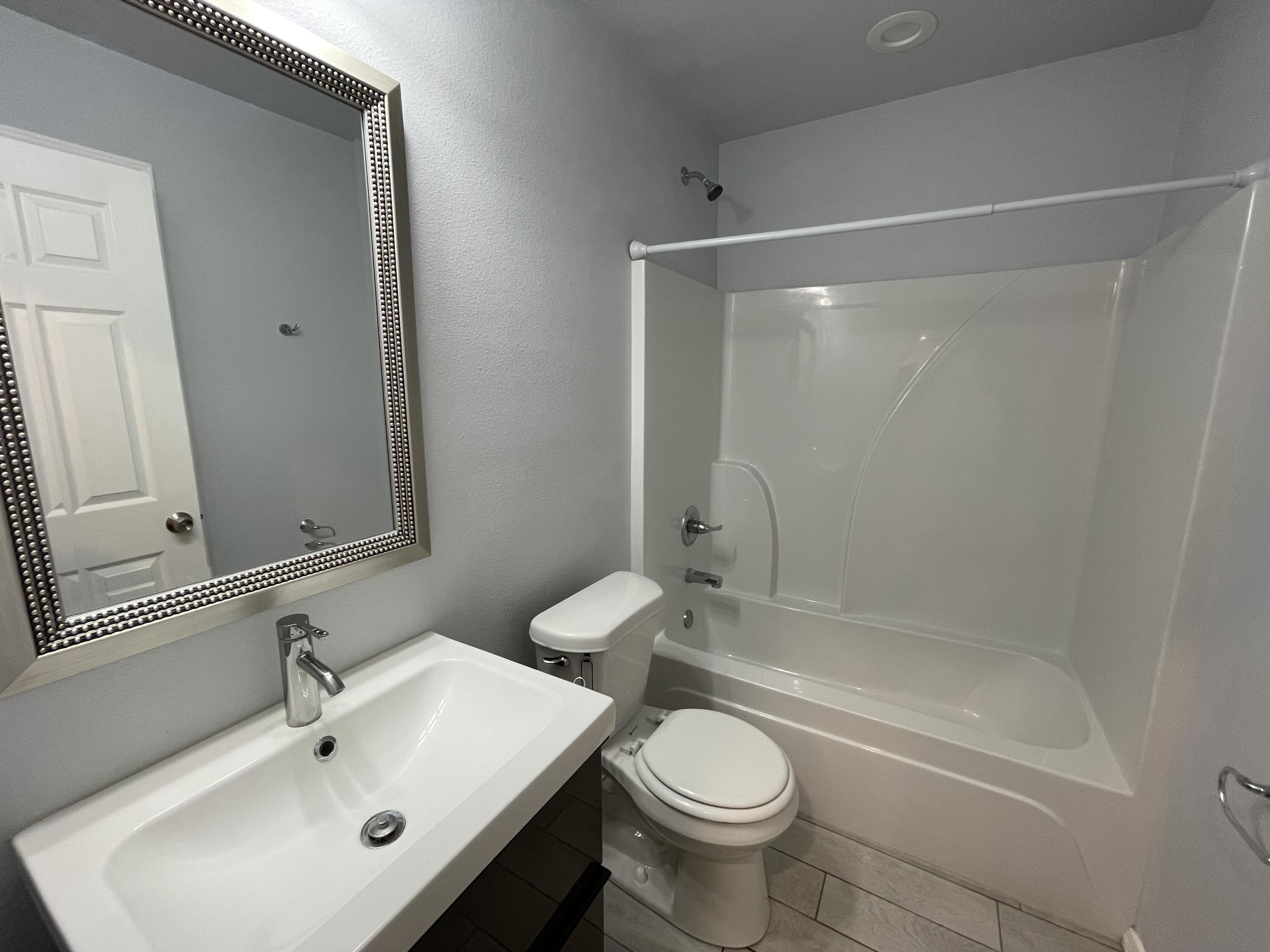 8410 11th Street Lubbock, TX 79416 - Photo 11 of 13 a bathroom with a sink mirror toilet and bathtub