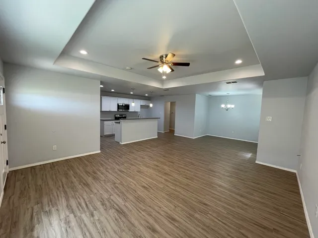 an empty room with wooden floor and a ceiling fan