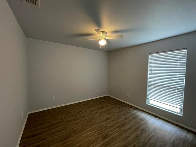 a view of empty room with wooden floor and fan