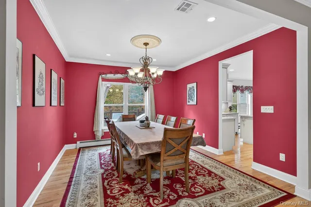 a dining room with wooden floor and chandelier