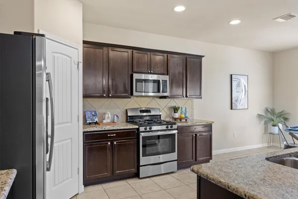 a kitchen with stainless steel appliances granite countertop a stove a sink and a refrigerator