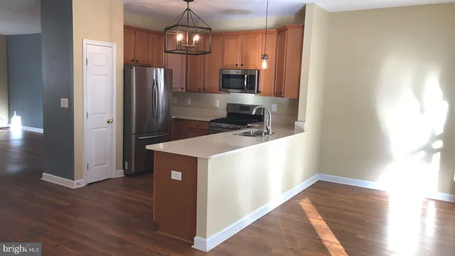 a kitchen with stainless steel appliances a refrigerator and a wooden floor