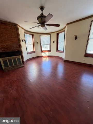 a view of an empty room with window and wooden floor