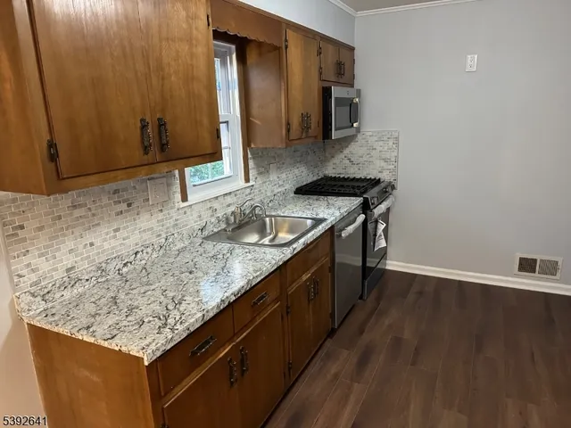 a kitchen with stainless steel appliances granite countertop a sink stove and cabinets