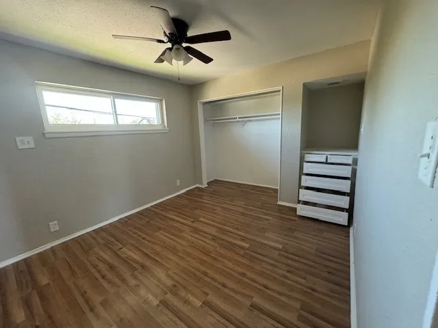 a view of empty room with wooden floor and fan