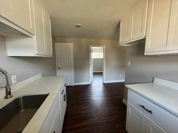 a kitchen with granite countertop white cabinets and a sink
