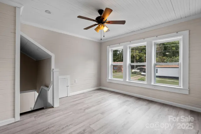 a view of an empty room with a window and wooden floor