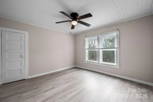a view of an empty room with wooden floor and a window