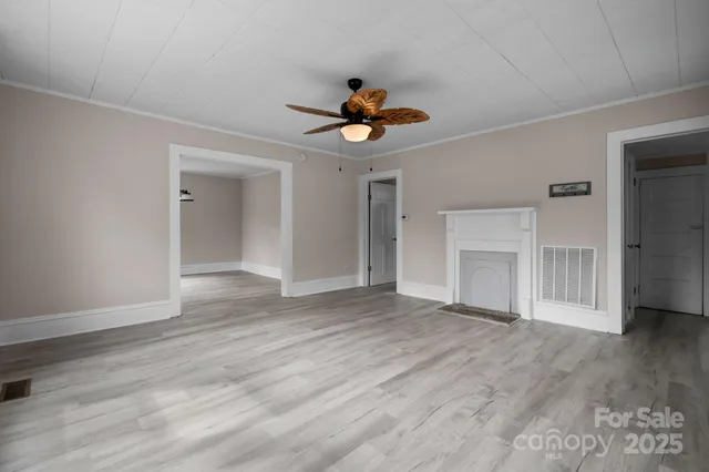 a view of empty room with wooden floor and ceiling fan