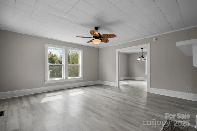 an empty room with wooden floor and chandelier fan