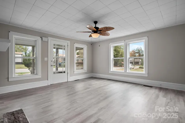 a view of an empty room with a window and wooden floor
