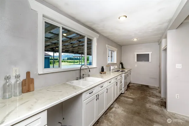 a large white kitchen with a sink and large window