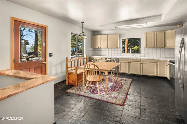 a large dining hall with stainless steel appliances granite countertop a stove a sink dishwasher and white cabinets with wooden floor