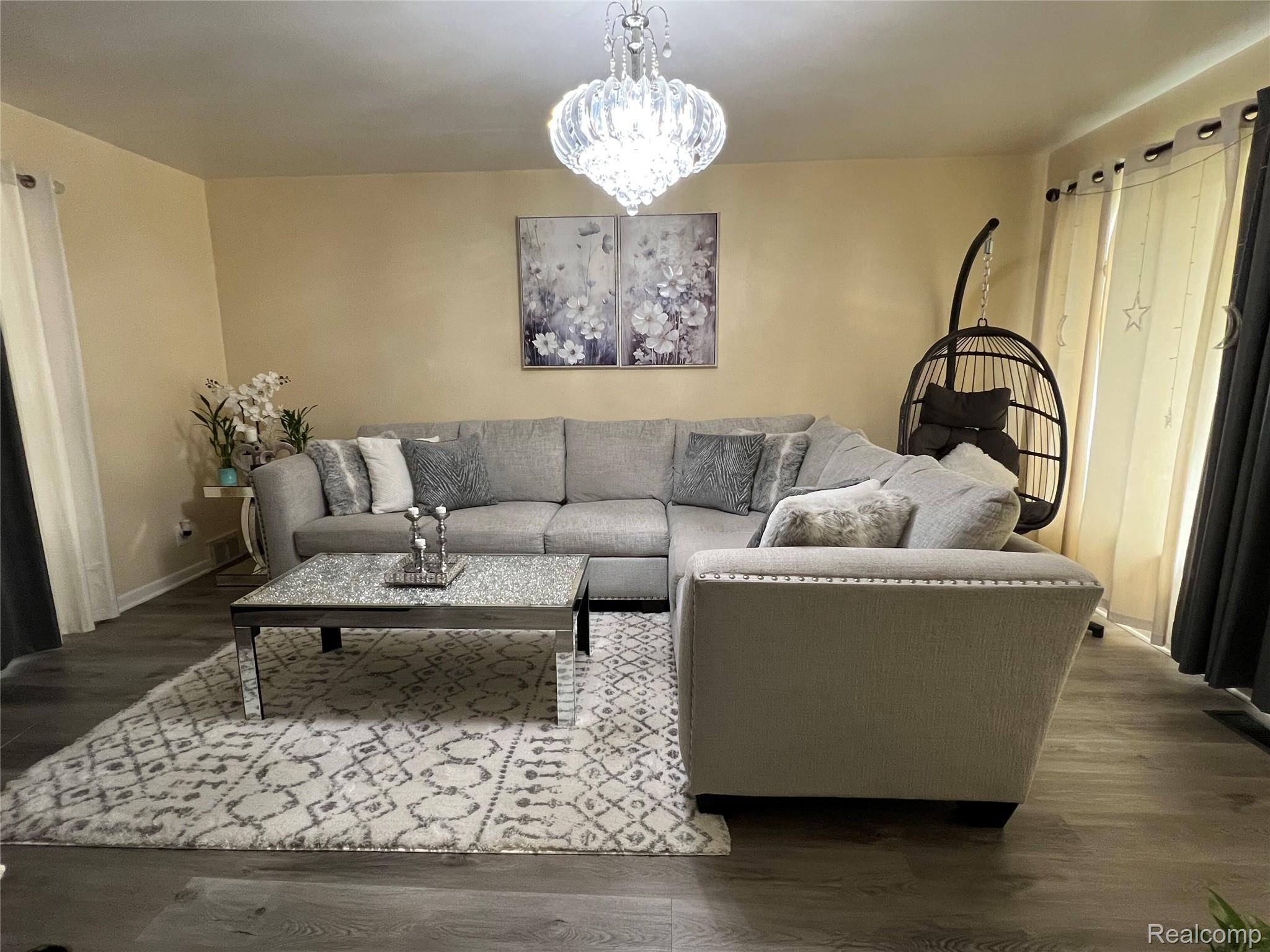 Modern chandelier, wood-finish flooring, light-toned walls