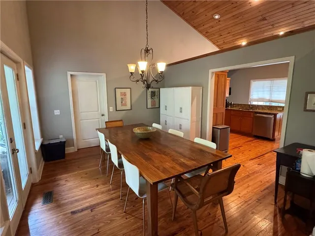 a dining room with wooden floor a chandelier a wooden table and chairs