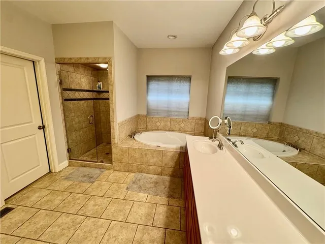 a bathroom with a tub a sink a mirror and a shower
