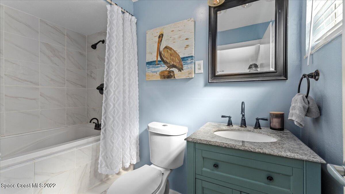 912 Bali Road Cocoa Beach, FL 32931 - Photo 21 of 48 a bathroom with a granite countertop toilet sink and mirror
