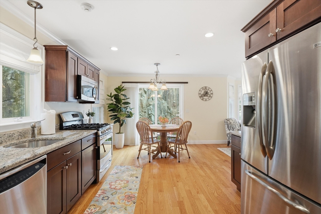 2 B Gates Lane, Unit B Wakefield, MA 01880 - Photo 6 of 42 a kitchen with stainless steel appliances granite countertop a refrigerator a sink dishwasher a stove and a dining table with wooden floor
