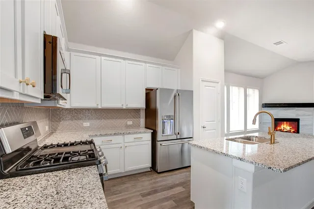 a kitchen with granite countertop a refrigerator stove top oven and sink