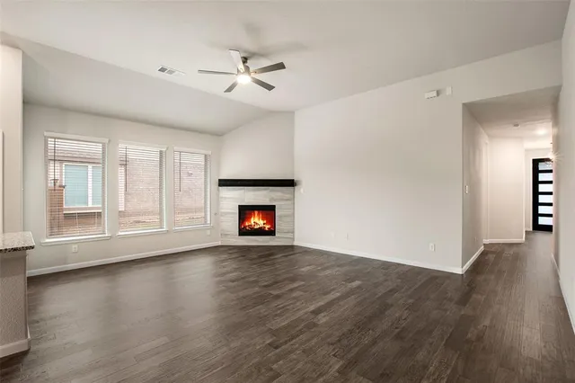 an empty room with wooden floor fireplace and windows