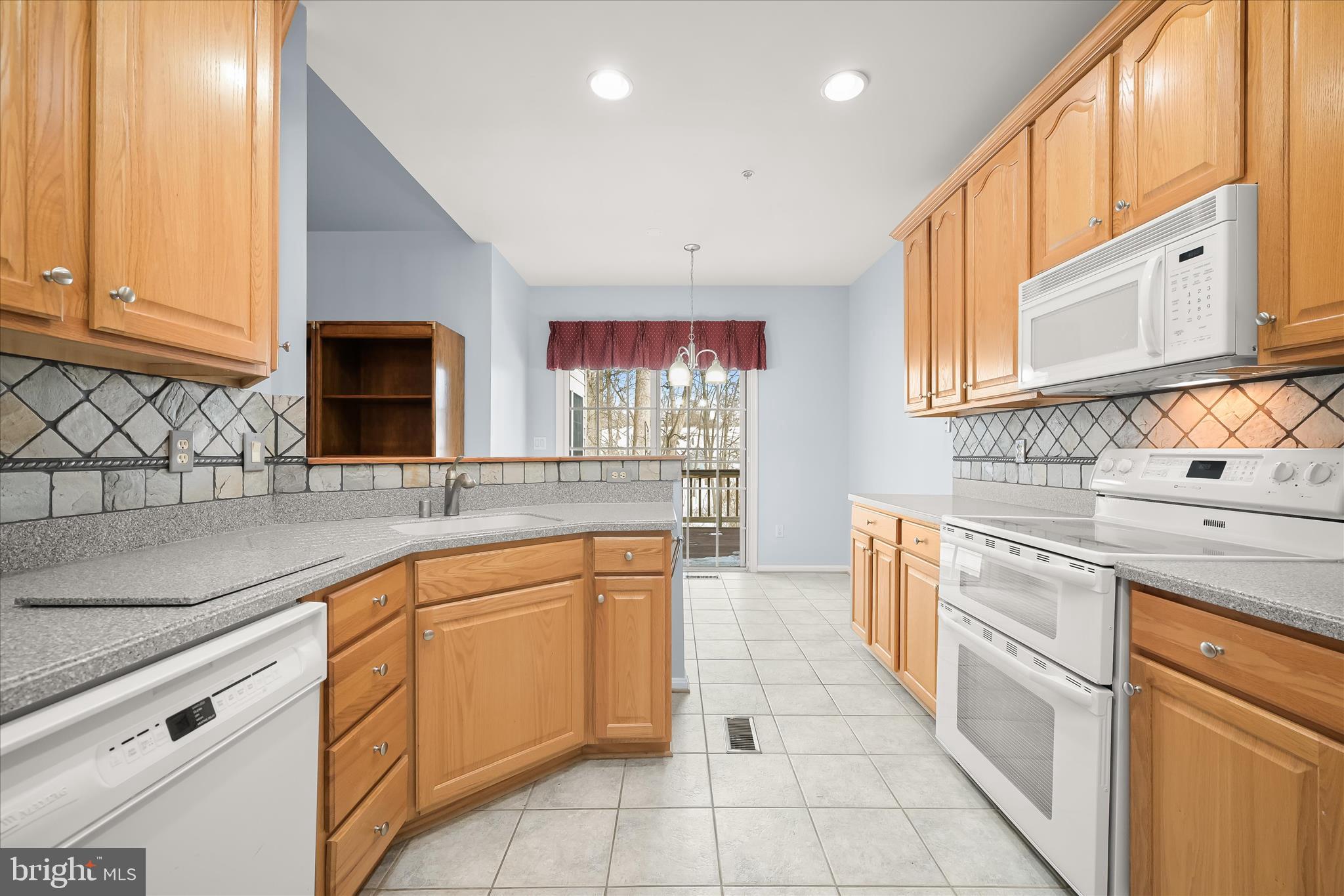 6428 Hickory Overlook, Unit 71 Columbia, MD 21044 - Photo 30 of 63 a kitchen with stainless steel appliances granite countertop a sink and dishwasher a stove top oven with wooden floor
