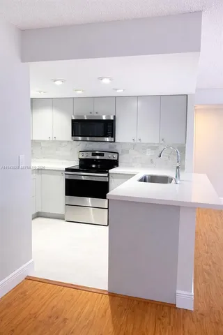 a kitchen with stainless steel appliances a sink a stove a microwave a sink a refrigerator and cabinets