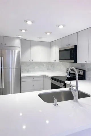 a kitchen with granite countertop a refrigerator a sink a stove a microwave a counter top space and cabinets