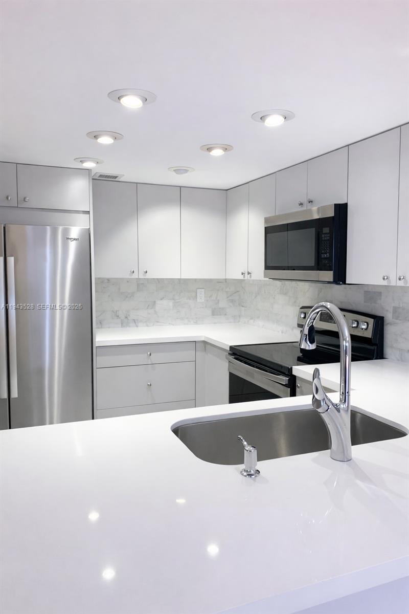 9033 Southwest 123rd Court, Unit 105 Miami, FL 33186 - Photo 6 of 11 a kitchen with granite countertop a refrigerator a sink a stove a microwave a counter top space and cabinets