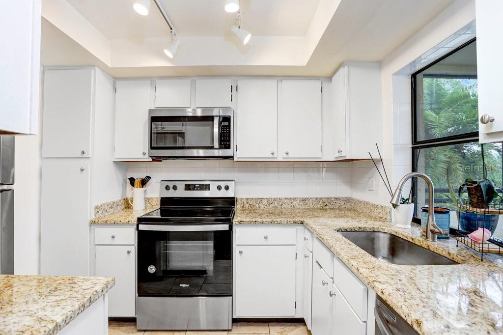 13602 South Village Drive, Unit 1205 Tampa, FL 33618 - Photo 12 of 51 a kitchen with granite countertop a stove sink and microwave