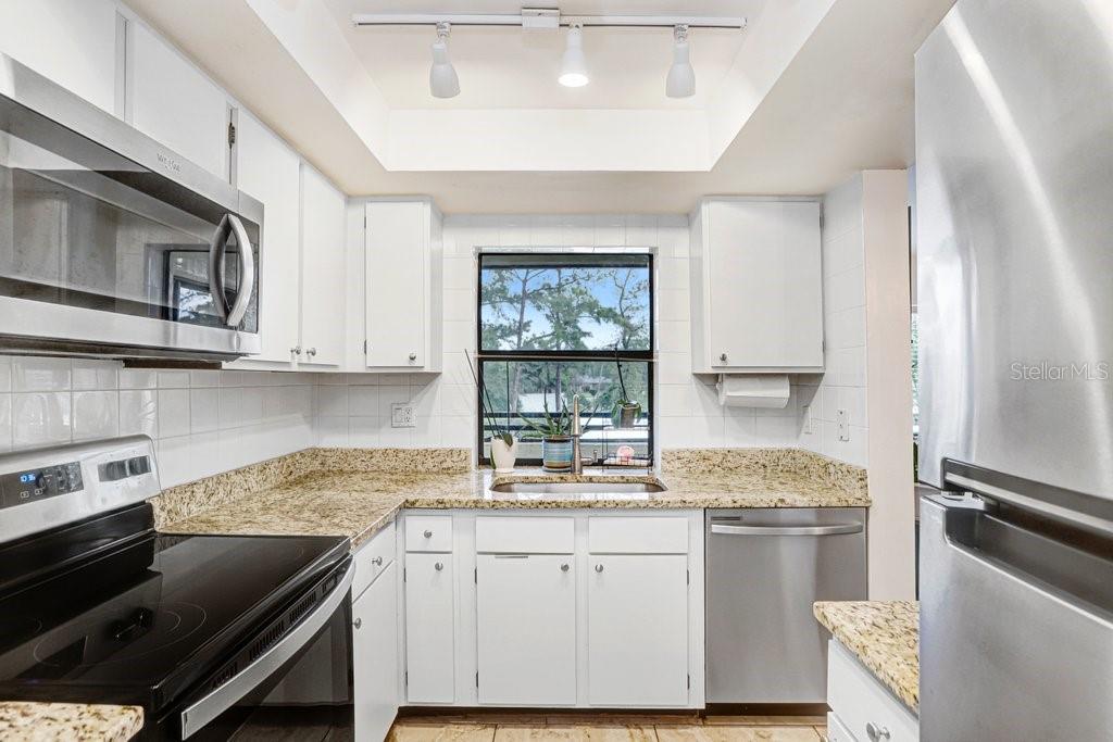 13602 South Village Drive, Unit 1205 Tampa, FL 33618 - Photo 14 of 51 a kitchen with granite countertop white cabinets white stainless steel appliances a sink and a window
