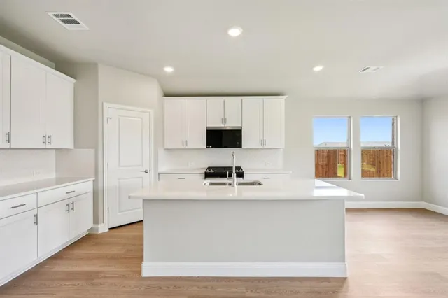 a kitchen with stainless steel appliances a white stove top oven and white cabinets