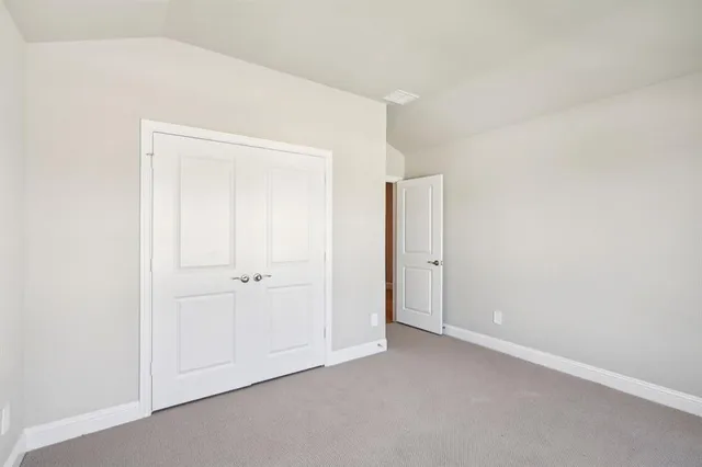 a large white kitchen with stainless steel appliances granite countertop a stove a sink a refrigerator and white cabinets with wooden floor