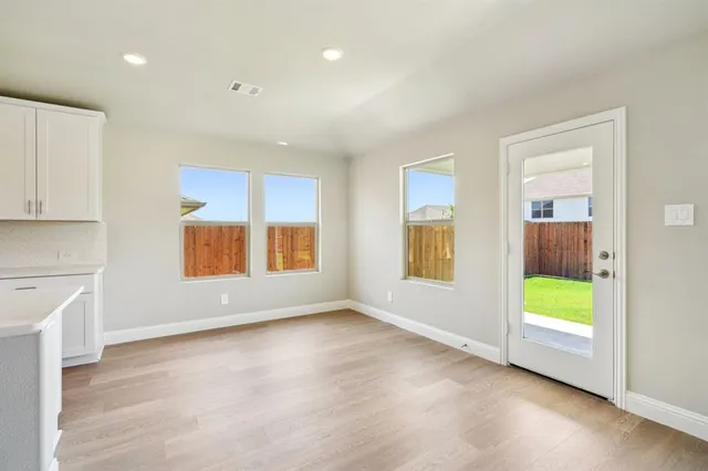 a view of kitchen with stove and white cabinets