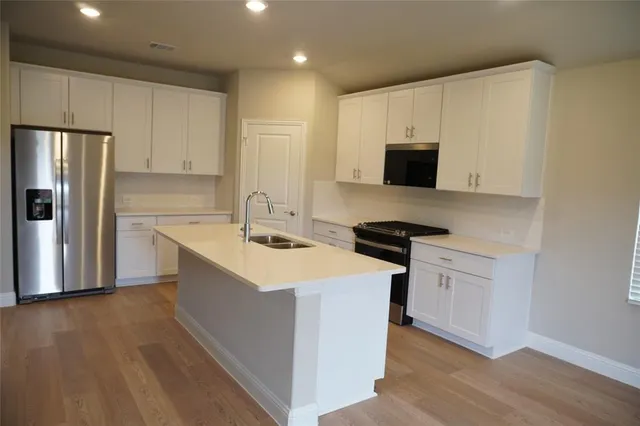 a view of an empty room with a window and a kitchen