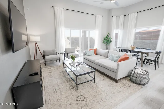 a living room with furniture a flat screen tv and a large window