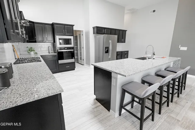 a kitchen with stainless steel appliances kitchen island granite countertop a kitchen island and chairs in it