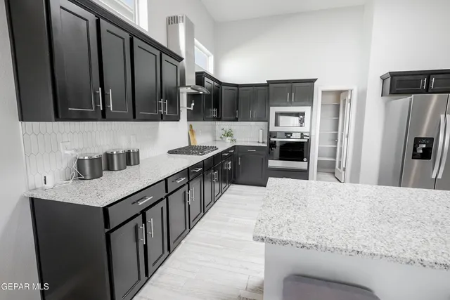 a kitchen with stainless steel appliances kitchen island granite countertop a sink stove and refrigerator