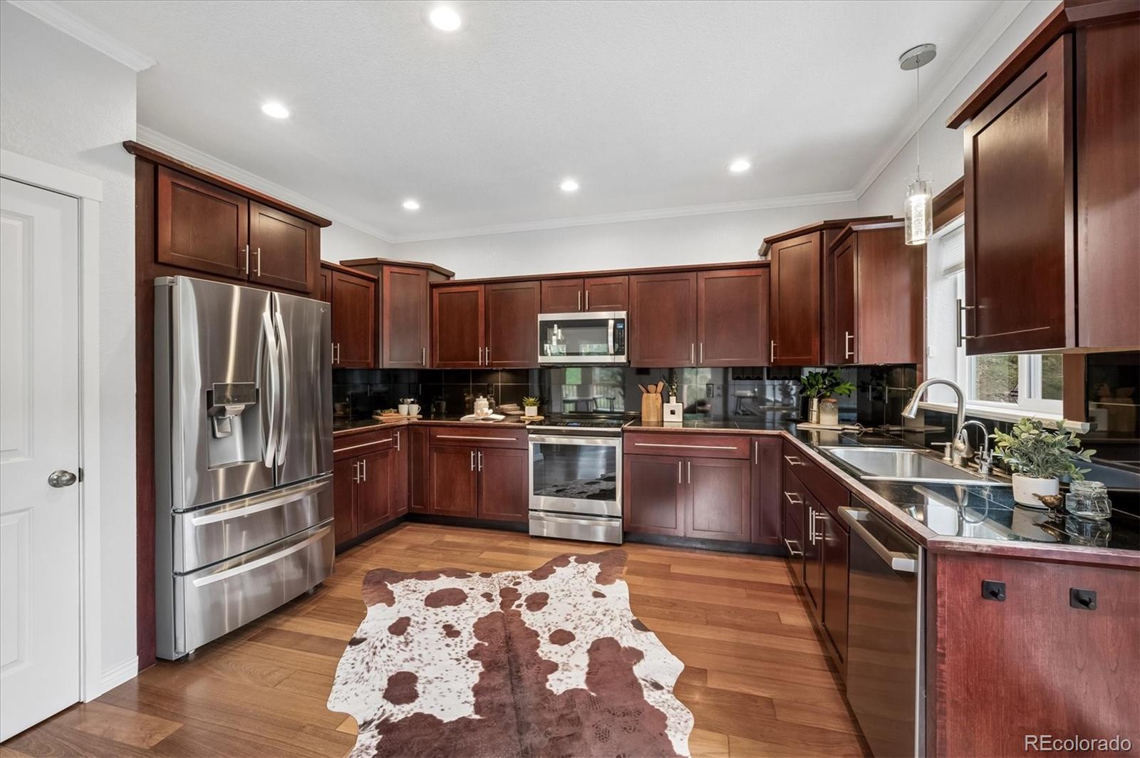 6747 South Brook Forest Road Evergreen, CO 80439 - Photo 10 of 49 a kitchen with stainless steel appliances granite countertop a refrigerator and wooden cabinets