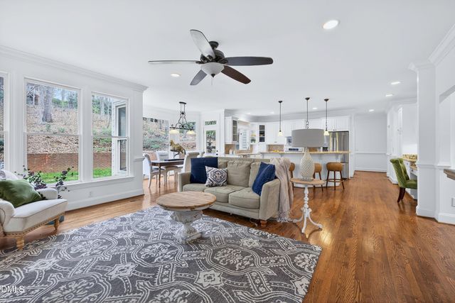 a open kitchen with stainless steel appliances granite countertop a stove top oven a sink a dining table and chairs with wooden floor