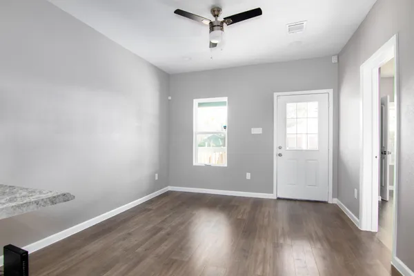 an empty room with wooden floor and windows