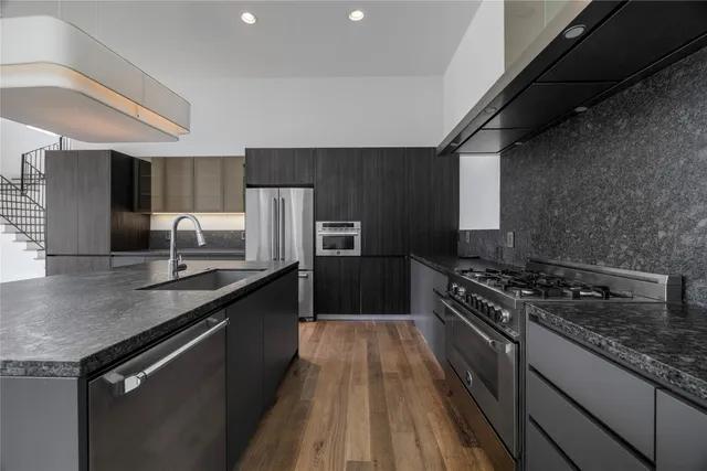 a kitchen with stainless steel appliances granite countertop a sink stove and refrigerator
