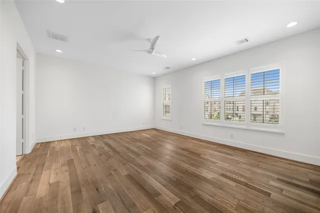 an empty room with wooden floor cabinet and windows