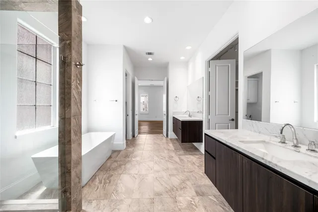 a spacious bathroom with a tub sink and mirror
