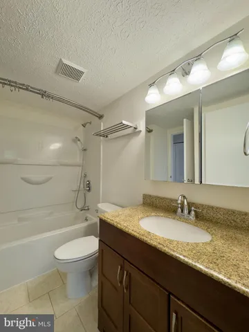 a bathroom with a granite countertop sink a toilet and shower