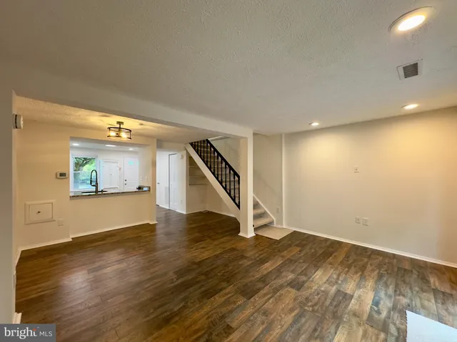 a view of an empty room with wooden floor and stairs